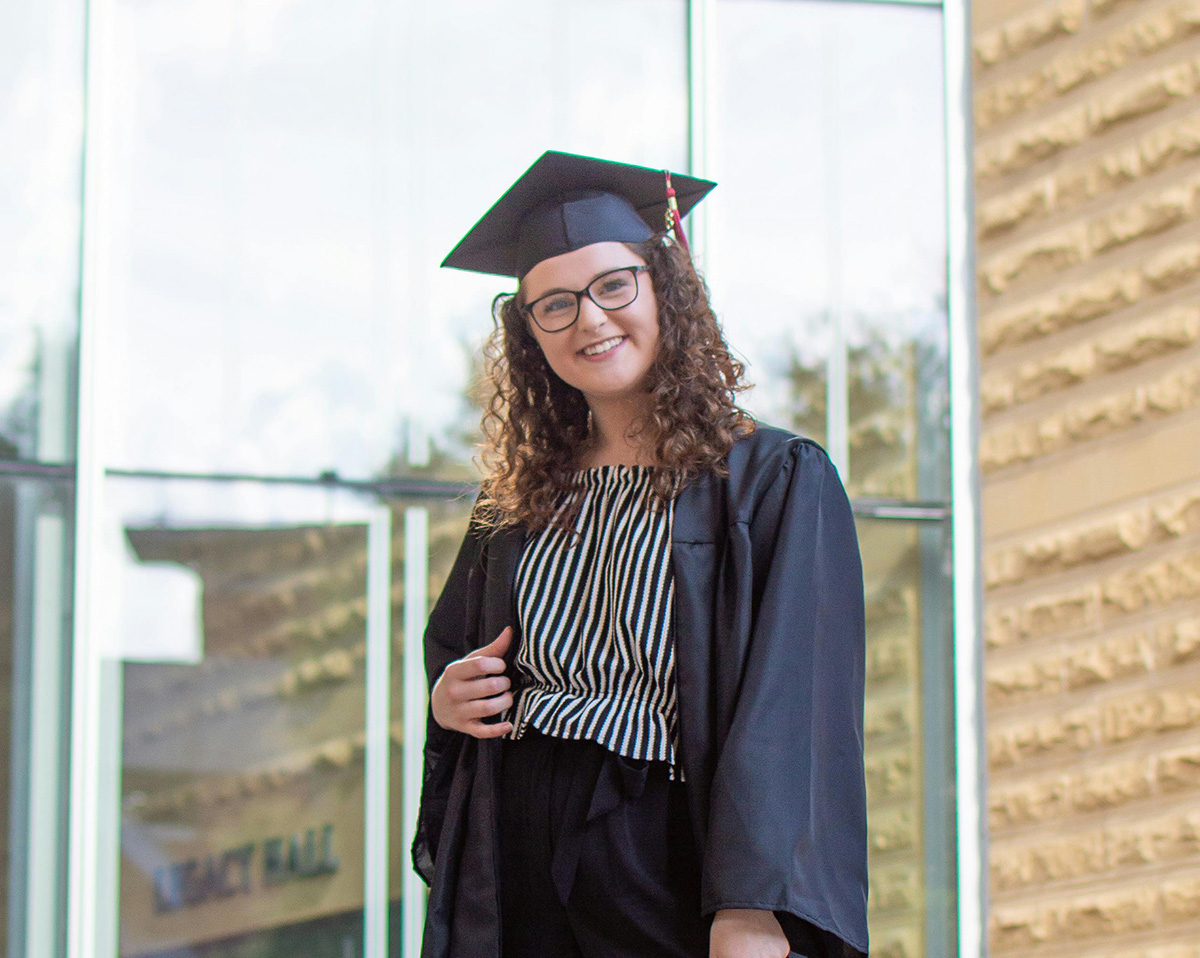 joven estudiante posa mirando a cámara. Viste toga y birrete
